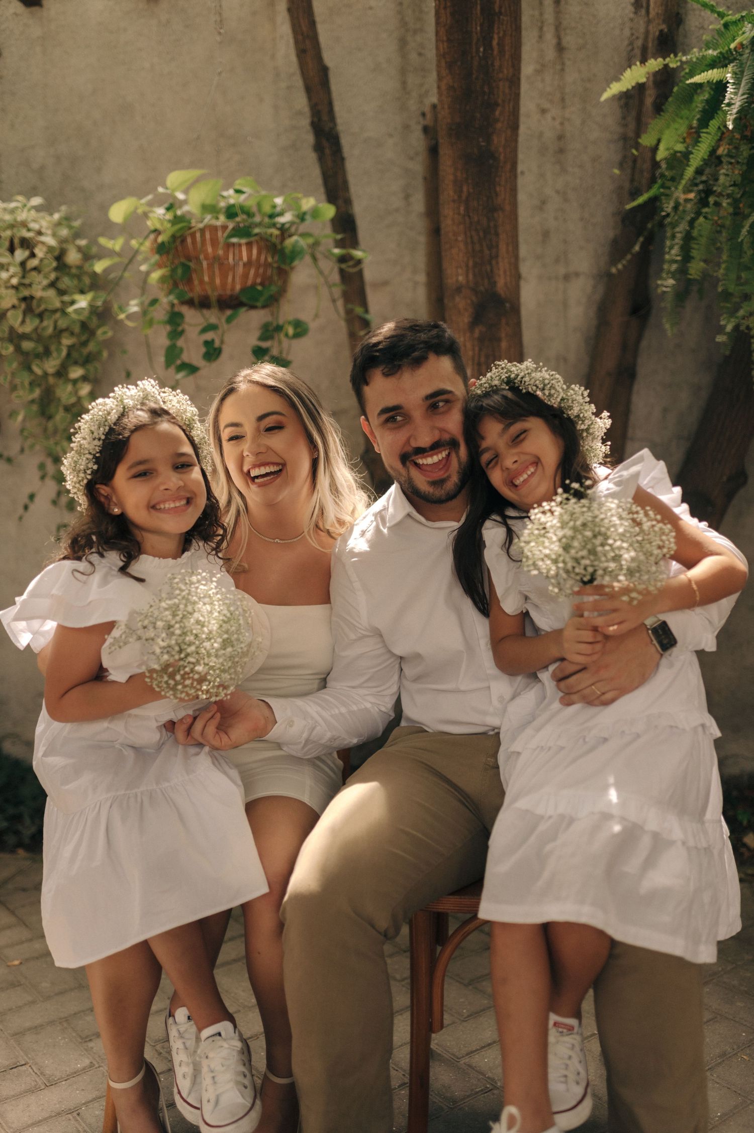 Happy family in white outfits poses together with baby's breath flowers.