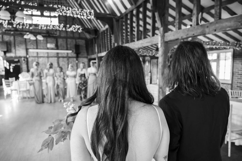 Back view of two guests watching wedding ceremony in timber-framed venue.