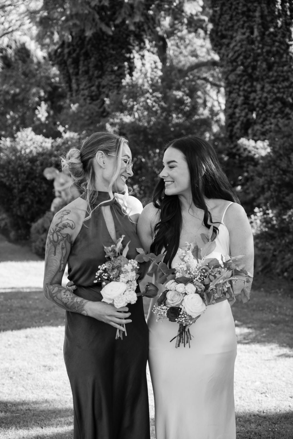 Black and white photo of couple sharing intimate moment with wedding flowers.