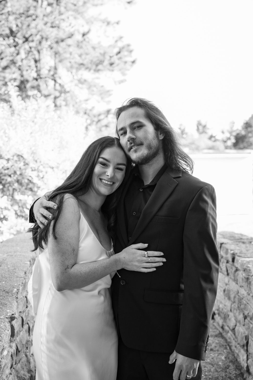 A black and white portrait of a couple embracing outdoors.
