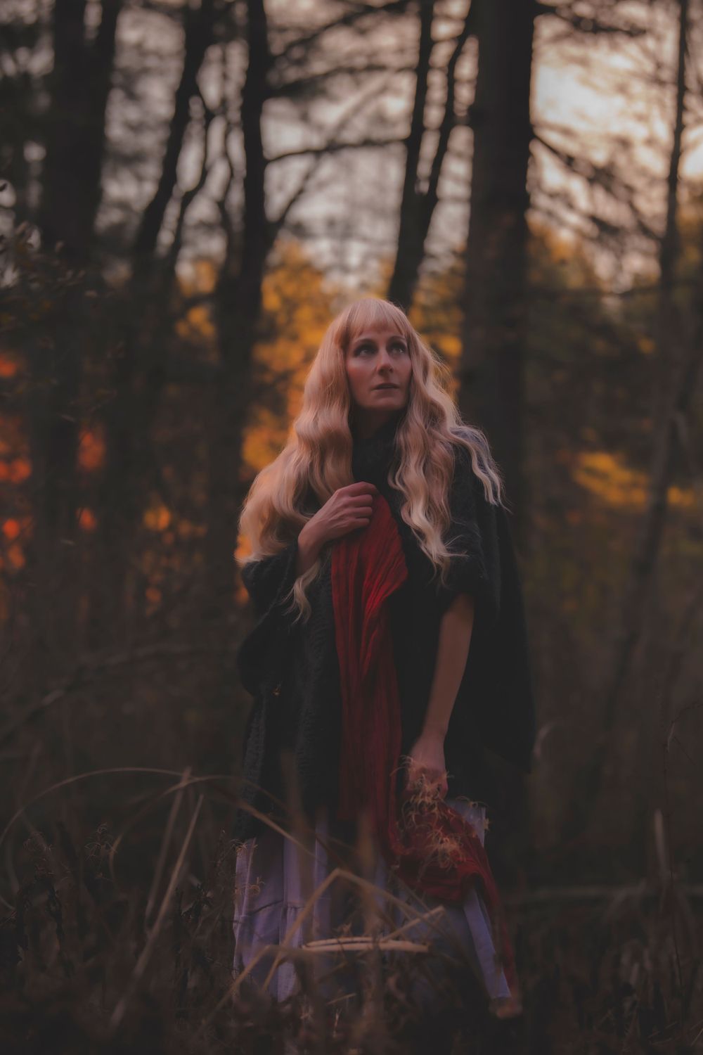 Artistic portrait in autumn woods features dramatic lighting and vintage-styled clothing.