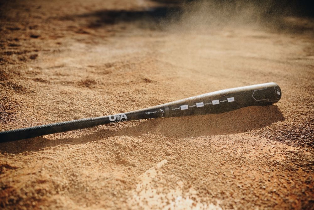 USA Baseball bat lying in sandy baseball diamond dirt with motion blur effect.