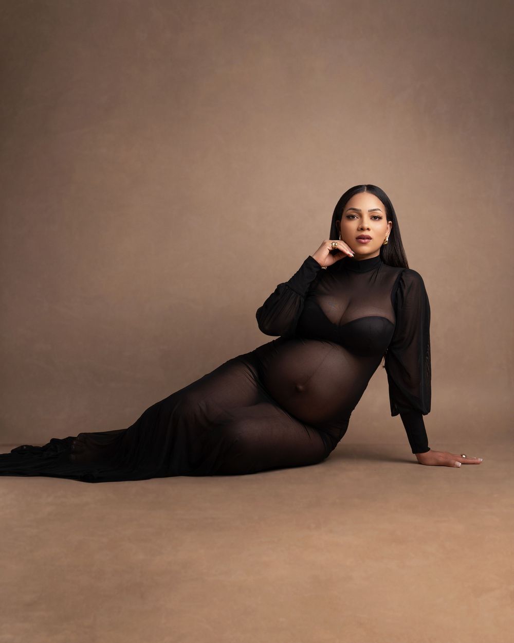 Artistic maternity photography series in black fabric against brown backdrop showing graceful reclining poses.