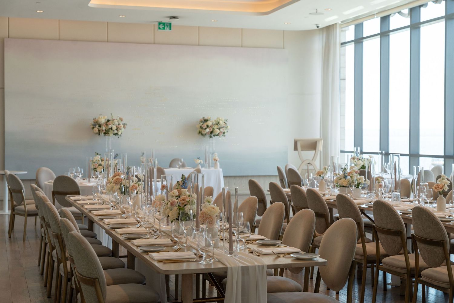 Modern banquet room with floor-to-ceiling windows and formal table settings for an upscale event.