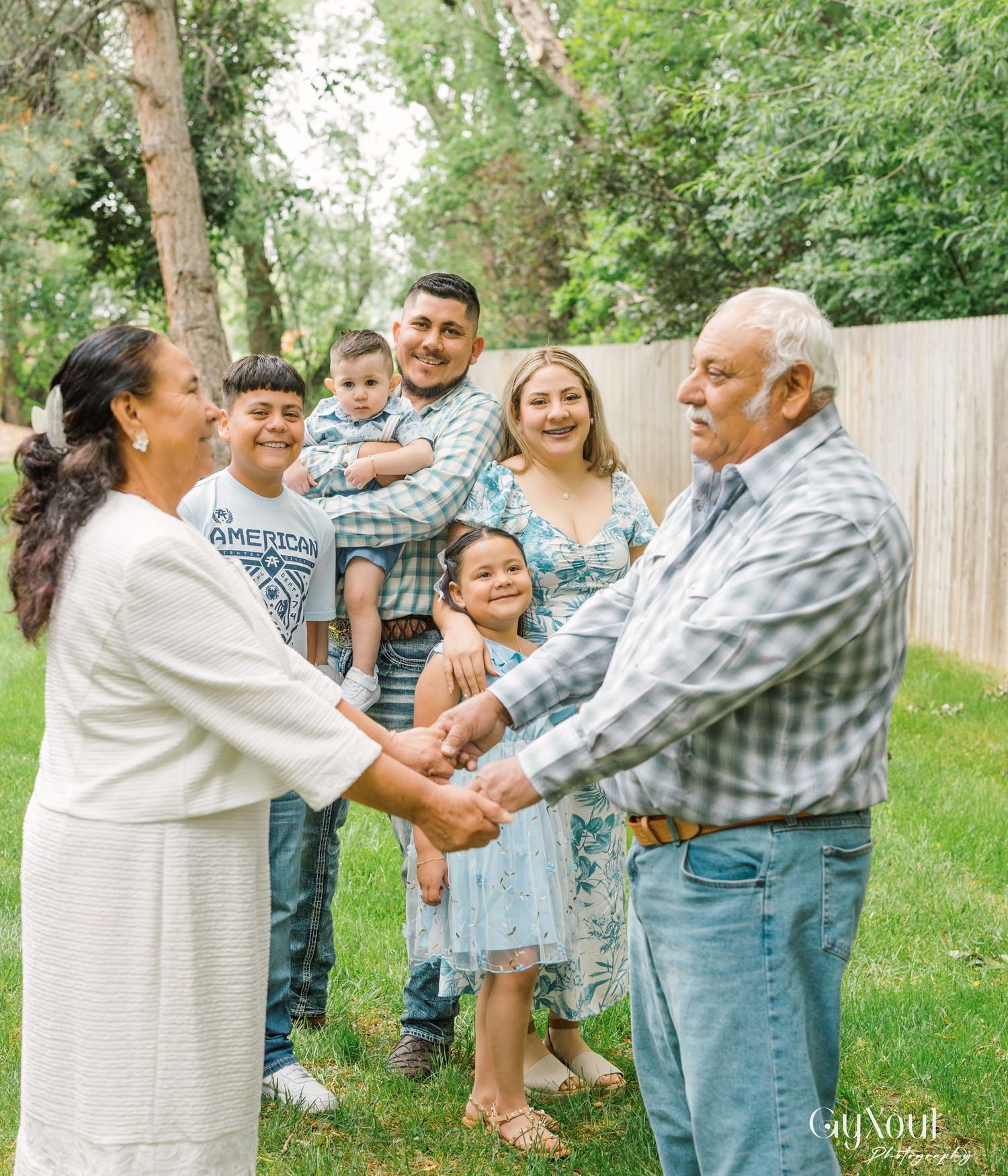 Happy group enjoying playful dance moves together in a backyard setting surrounded by lush greenery.