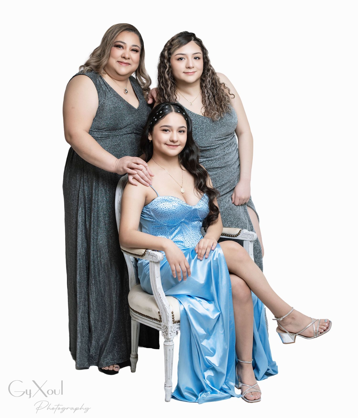 Three women in matching gray dresses pose together against a white background for a studio photoshoot.