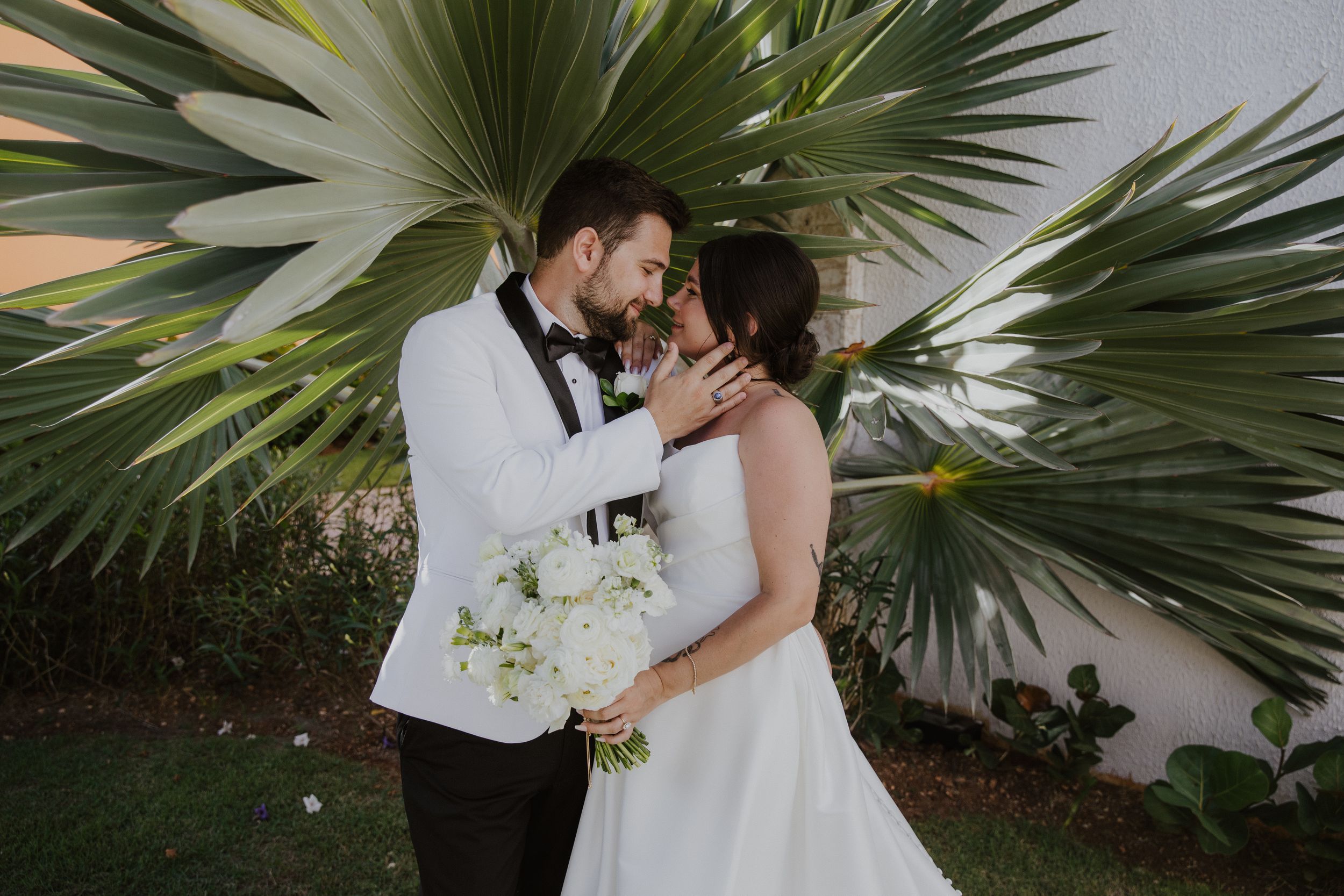 Dreams macao beach couple with white bouquet against tropical palm fronds.