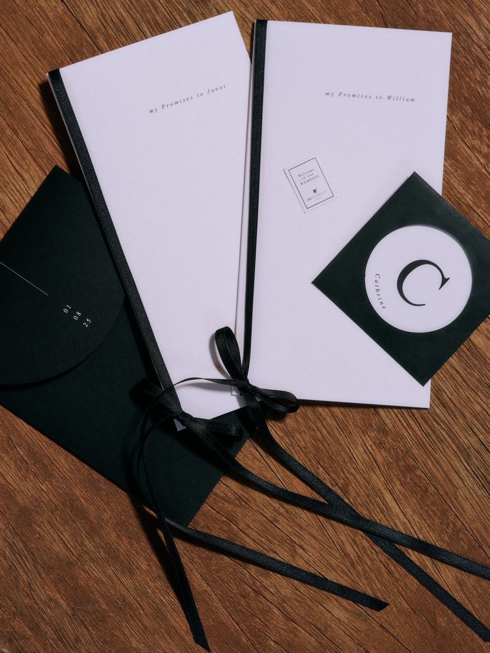 Wedding stationery set with white envelopes, black ribbons, and CD on wooden surface. Photoshoot by Venice Photographer Alina Indi