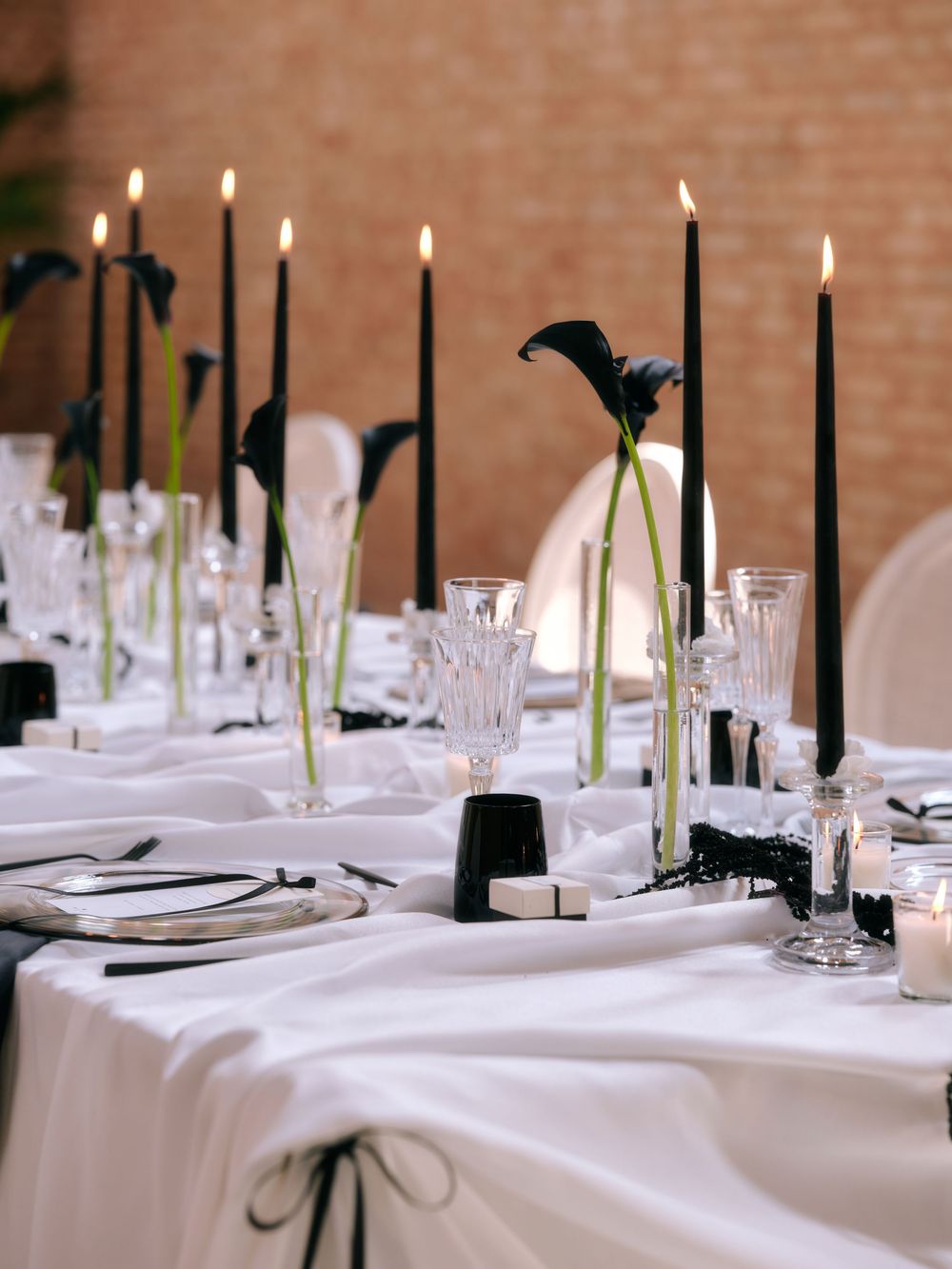 Wedding reception table with black taper candles and crystal glassware on white linens. Photoshoot by Venice Photographer Alina Indi