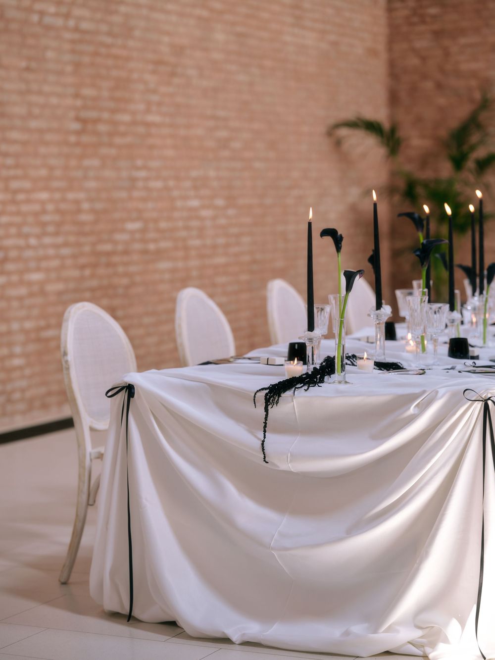 Minimalist wedding table with white tablecloth, black candles, and modern white chairs. Photoshoot by Venice Photographer Alina Indi
