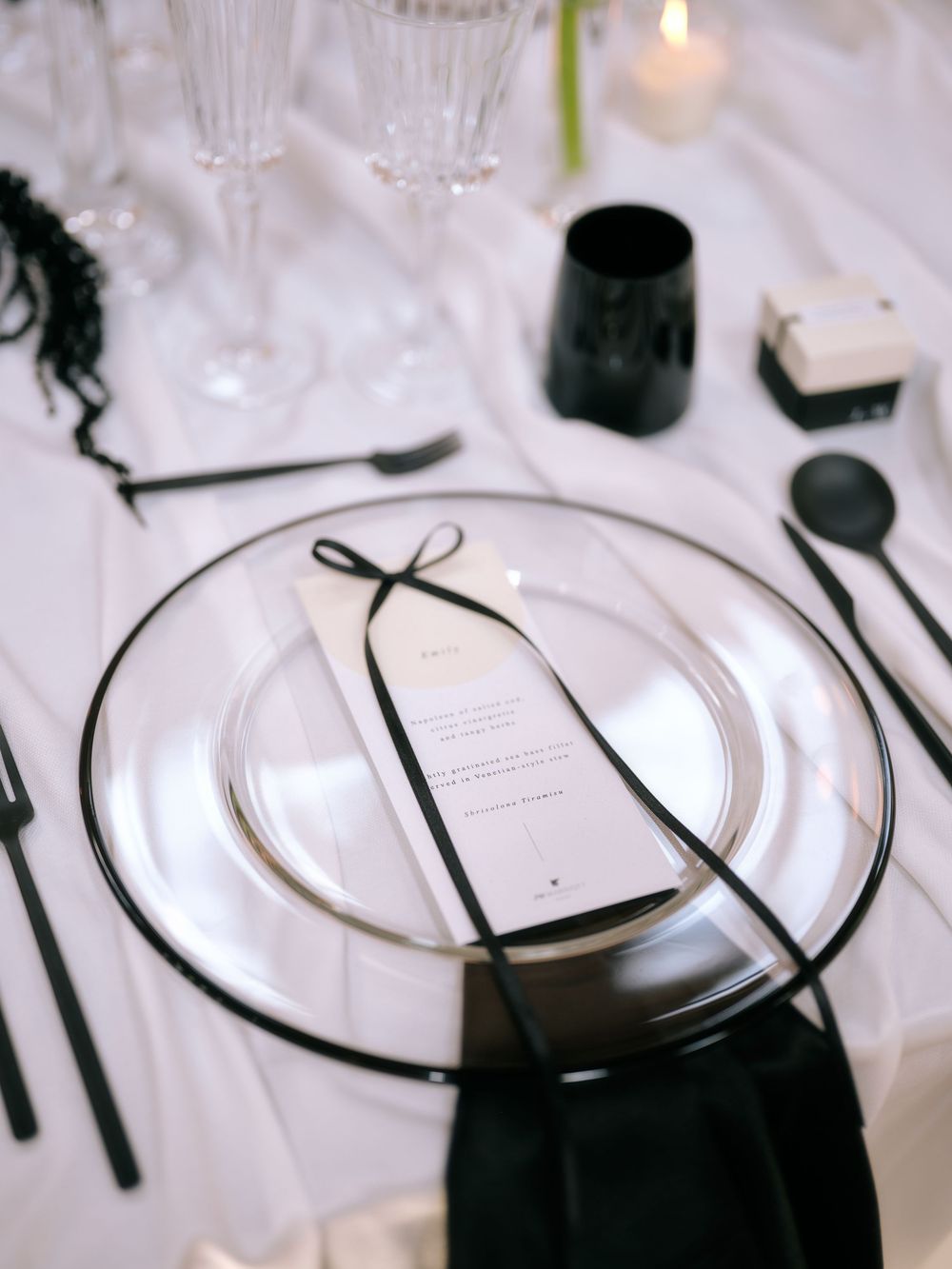 Elegant place settings with black ribbons and white plates on a formal dining table. Photoshoot by Venice Photographer Alina Indi