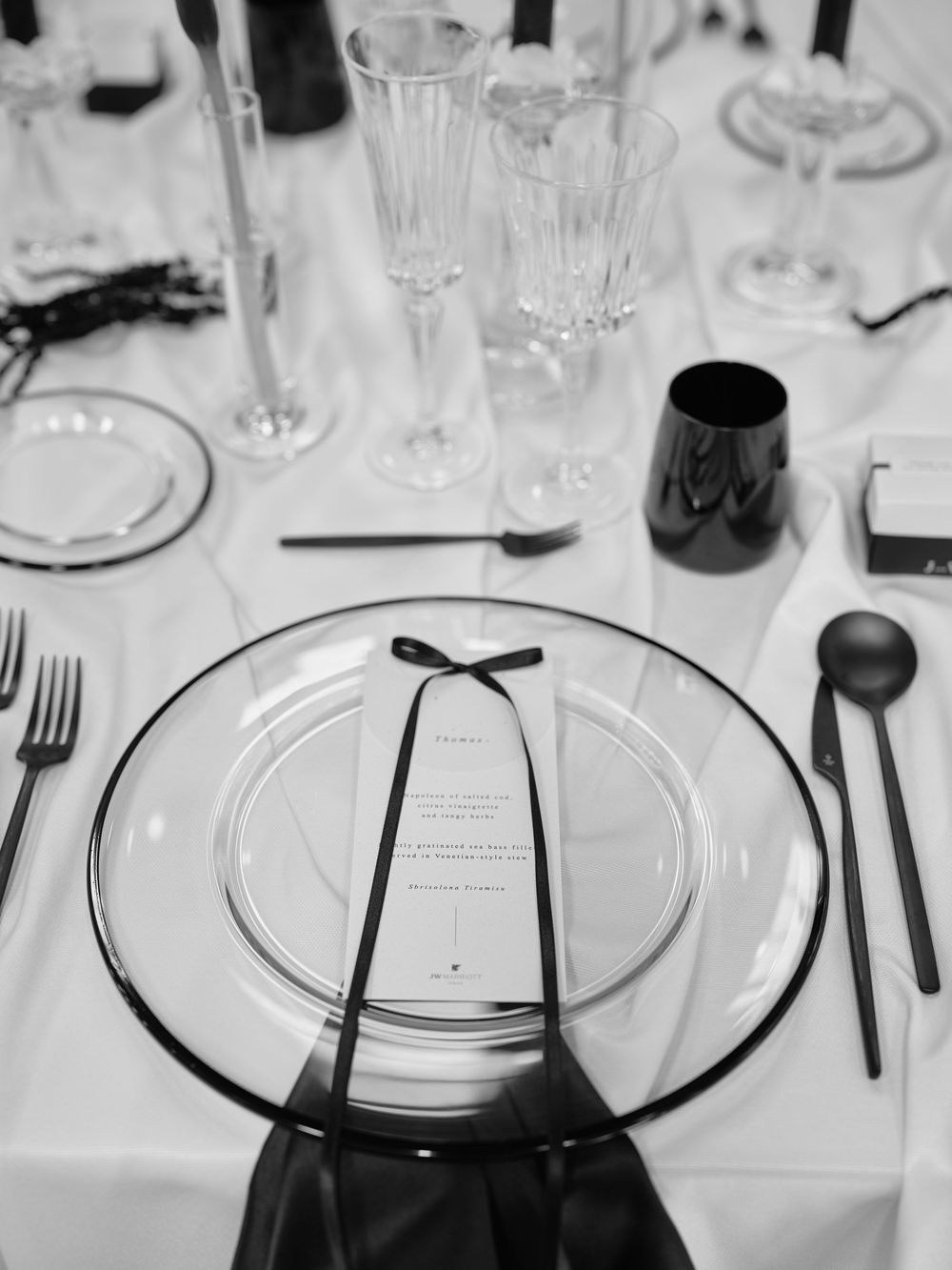 Minimalist table settings featuring clear charger plates and black accents on white linens. Photoshoot by Venice Photographer Alina Indi