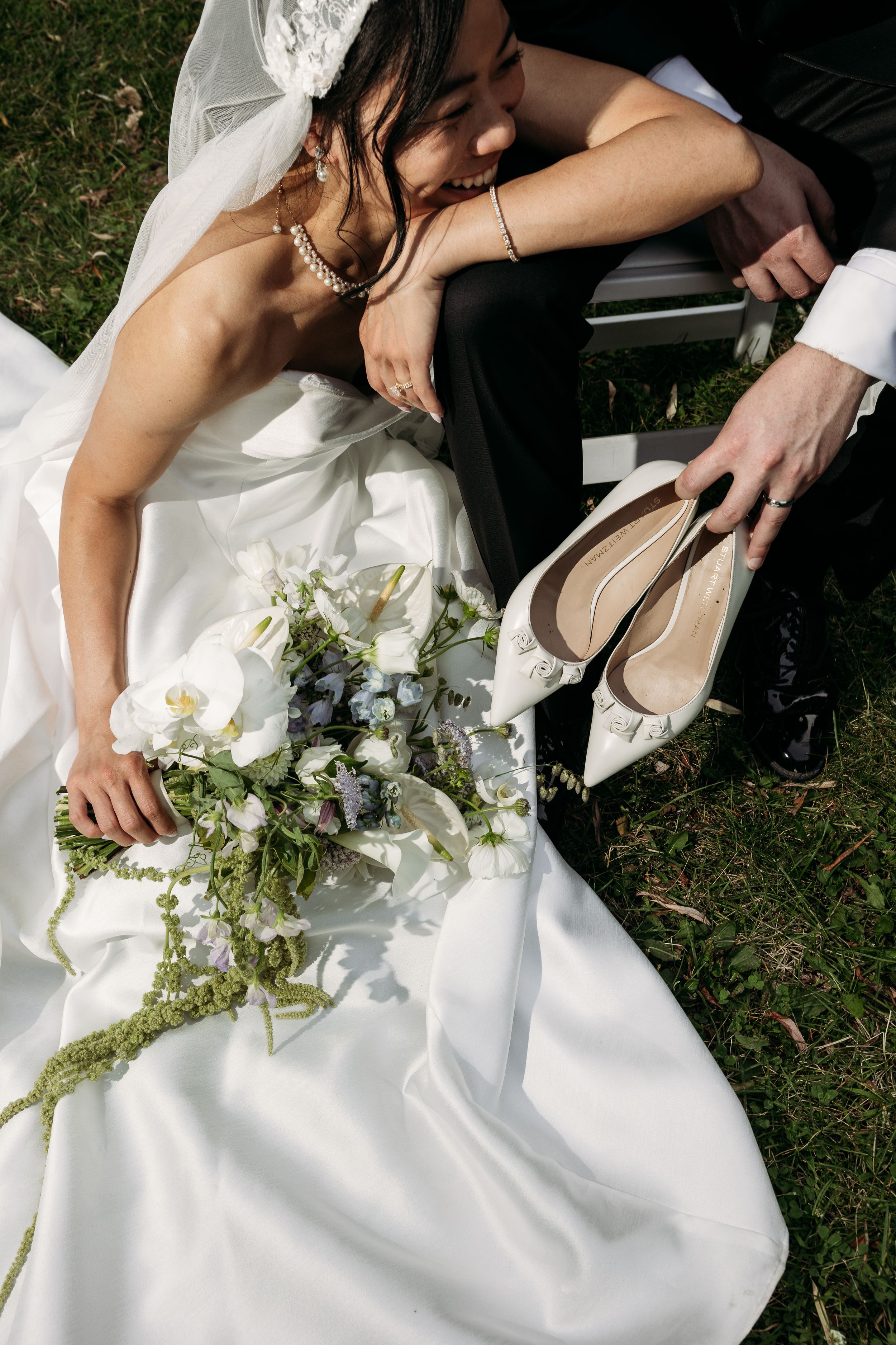 A collection of wedding detail shots showing a couple sitting on grass with white dress and floral bouquet details.