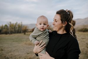 Family sharing tender moment together in open field with mountains in background.