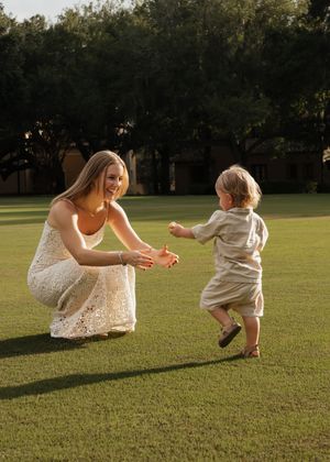 A parent and child playing together on a grassy lawn at sunset.