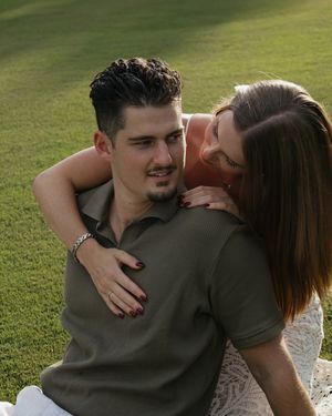 Intimate moment shared between couple in white dress and olive shirt on sunny day.