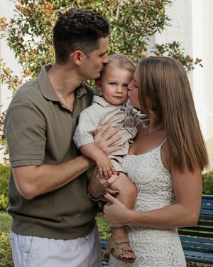 Family shares intimate moment together outdoors wearing coordinated white and olive outfits.