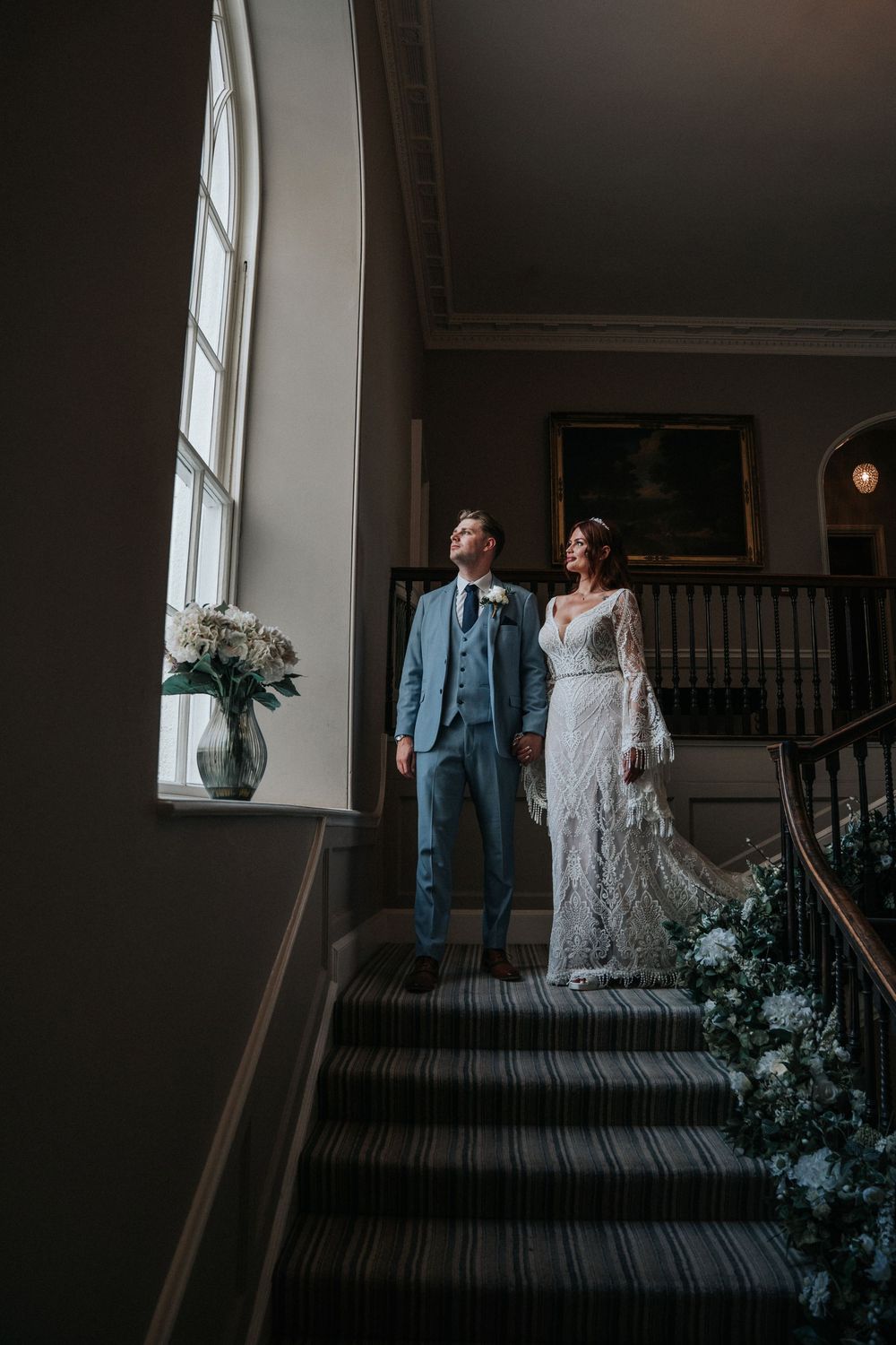 Bride and Groom looking out of the window at Rockbeare Manor grand staircase