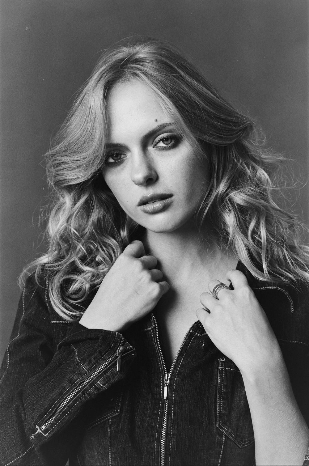 Dramatic black and white portrait with flowing hair and denim jacket.