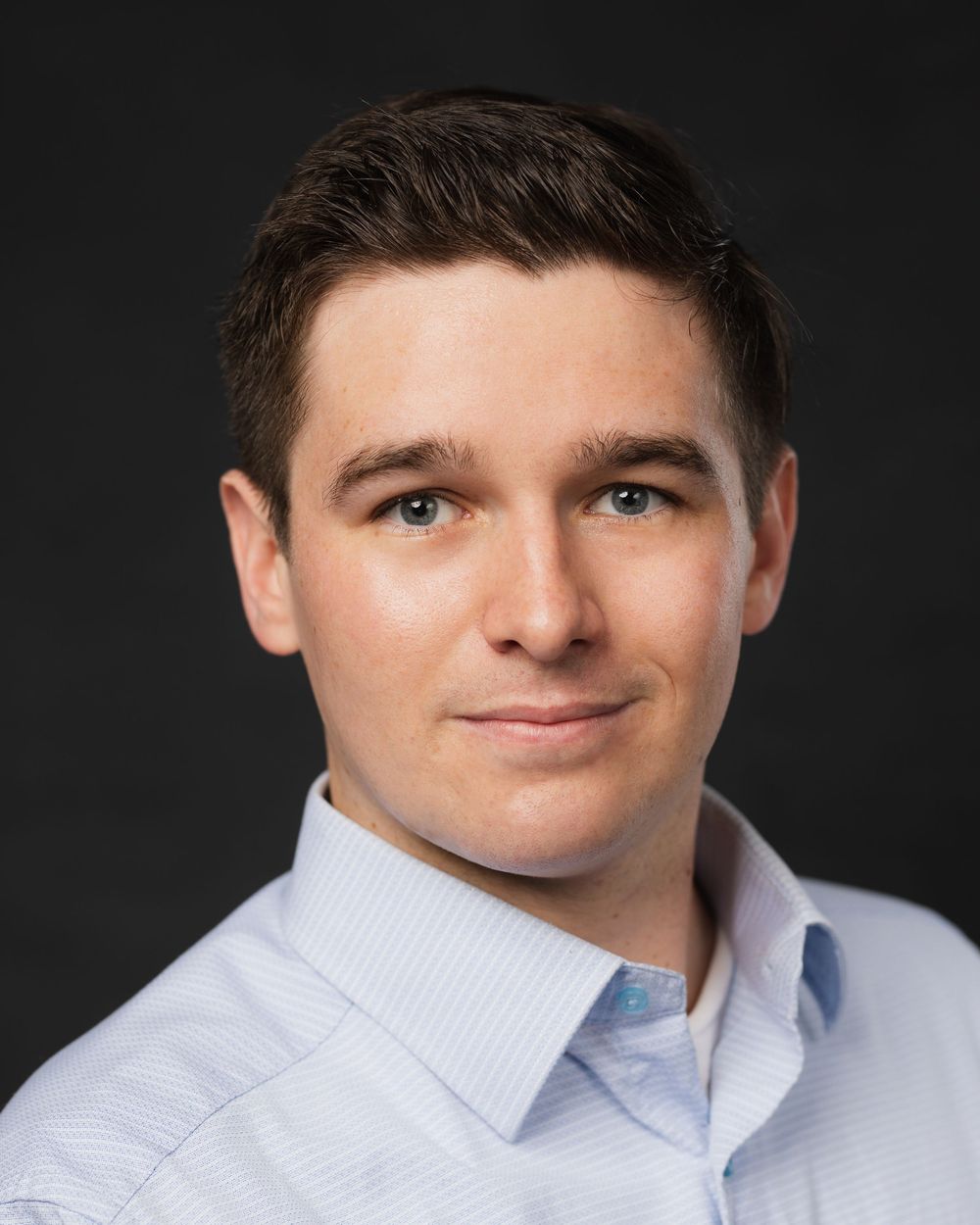 Professional headshot series of person in light blue dress shirt against dark background.