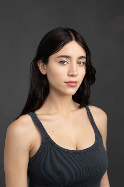 Studio portrait of woman in black tank top against dark background.