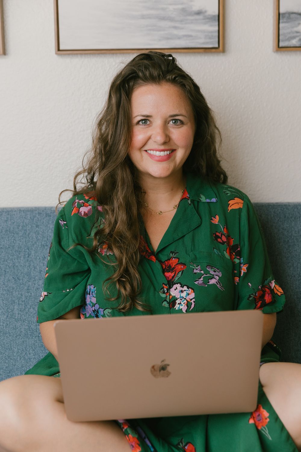 Person working on laptop wearing green floral dress in home office setting.