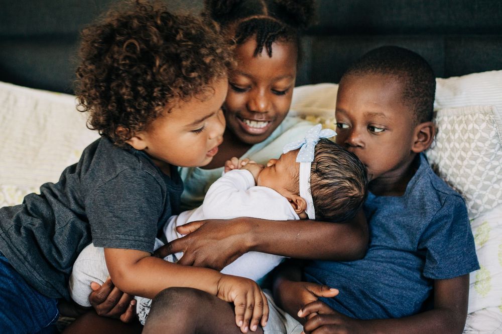 siblings smile at baby