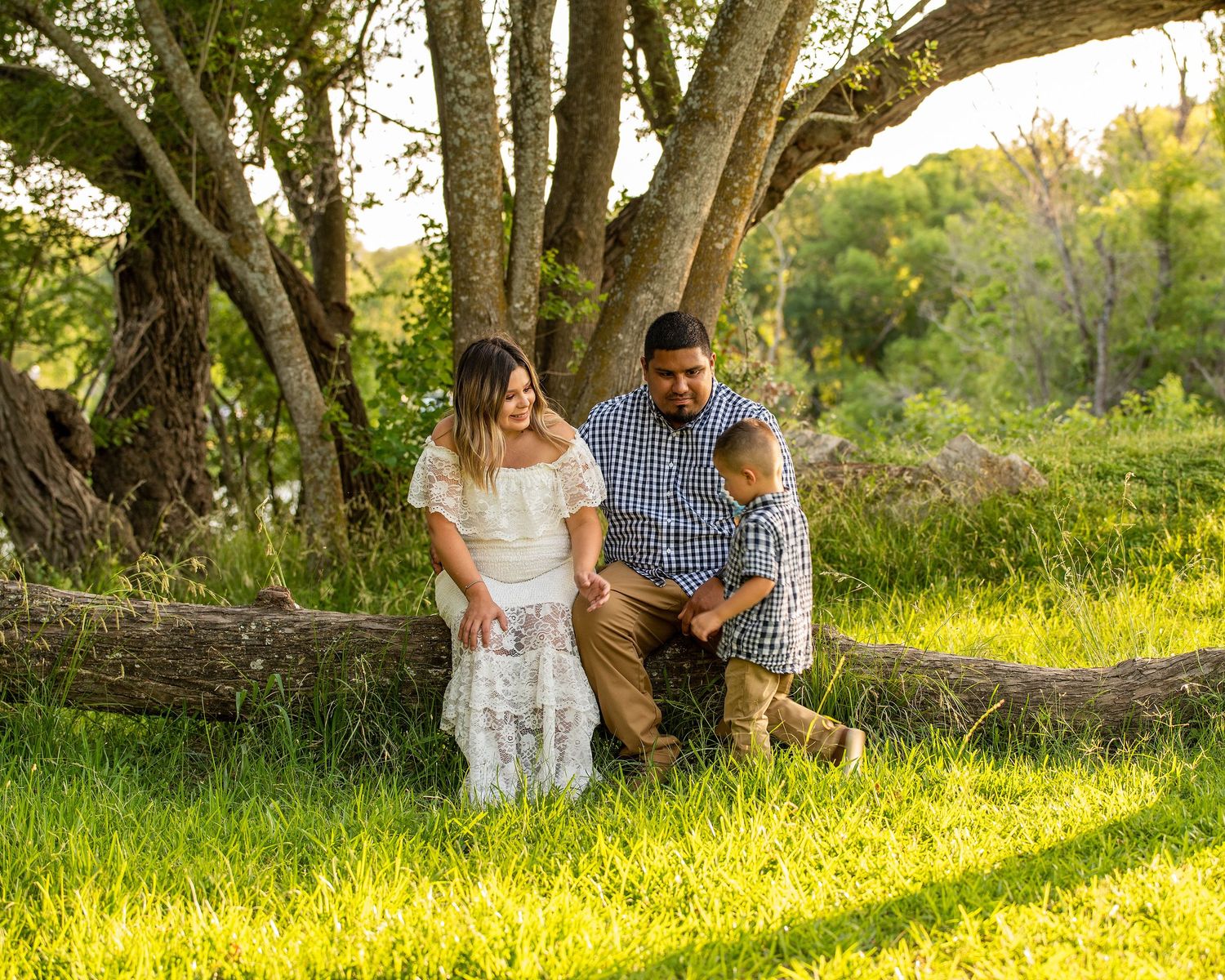 A playful interaction between parent and child during a sun-drenched outdoor photo session in a grassy field.