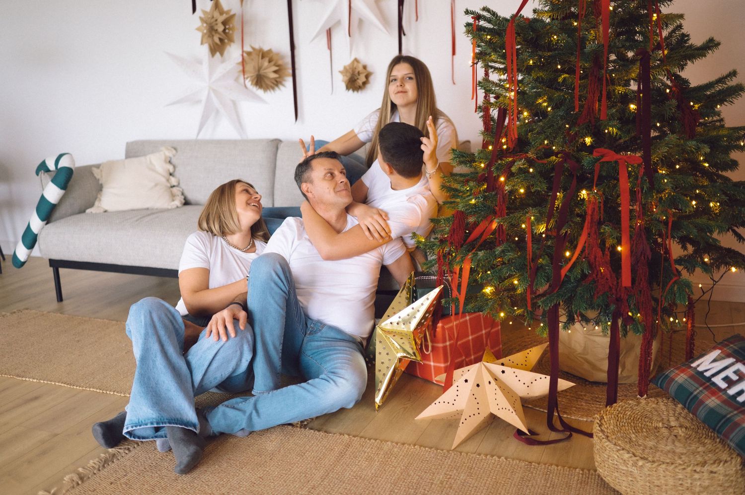 Four sequential views of a cozy Christmas scene with a decorated tree and presents arranged by the fireplace.