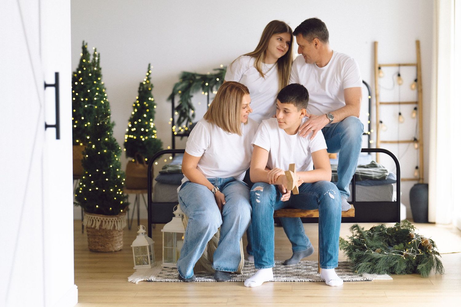 A family sits together at home during the holidays with a decorated Christmas tree in the background.