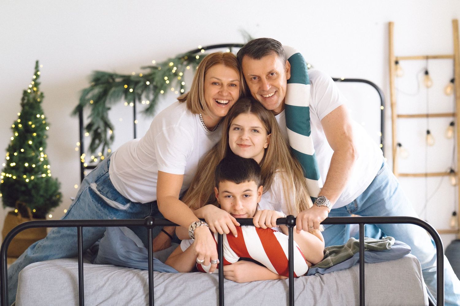 Family members relaxing together on gray sofa during winter holiday photoshoot with Christmas decor.