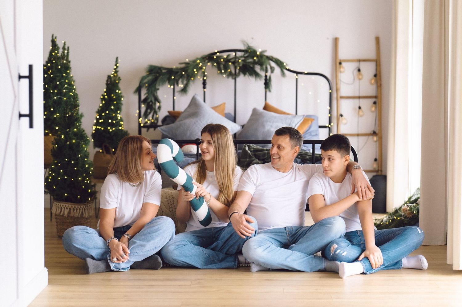 Series of romantic poses showing couple lounging on hardwood floor near white ladder and festive greenery.