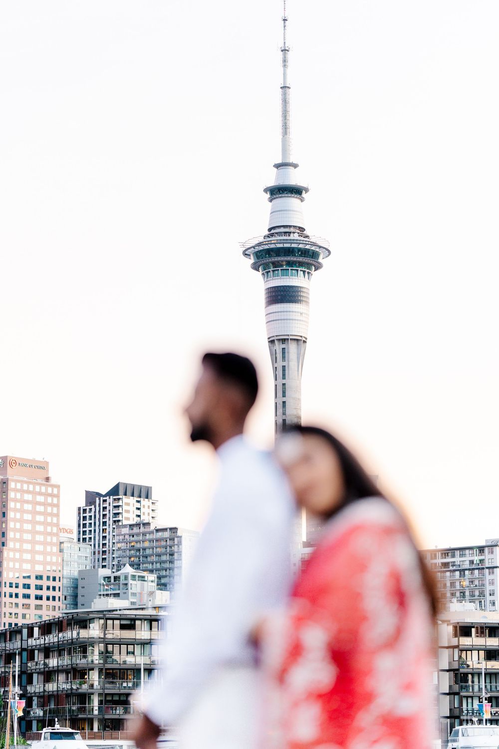 Blurred people walk along an urban street with the Sky Tower rising in the background in Auckland, New Zealand.