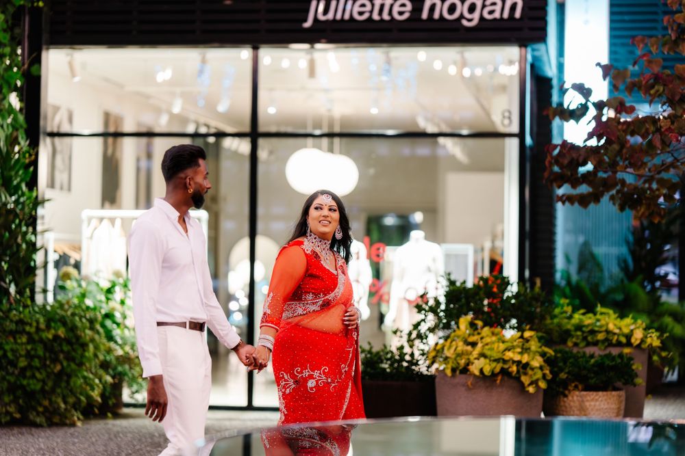 Two people chatting and laughing outside a Juliette Hogan storefront with decorative plants and flowers.