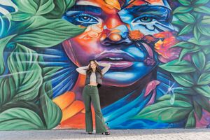 Colorful street art mural featuring vibrant blues, oranges and greens with tropical leaves against an urban wall.