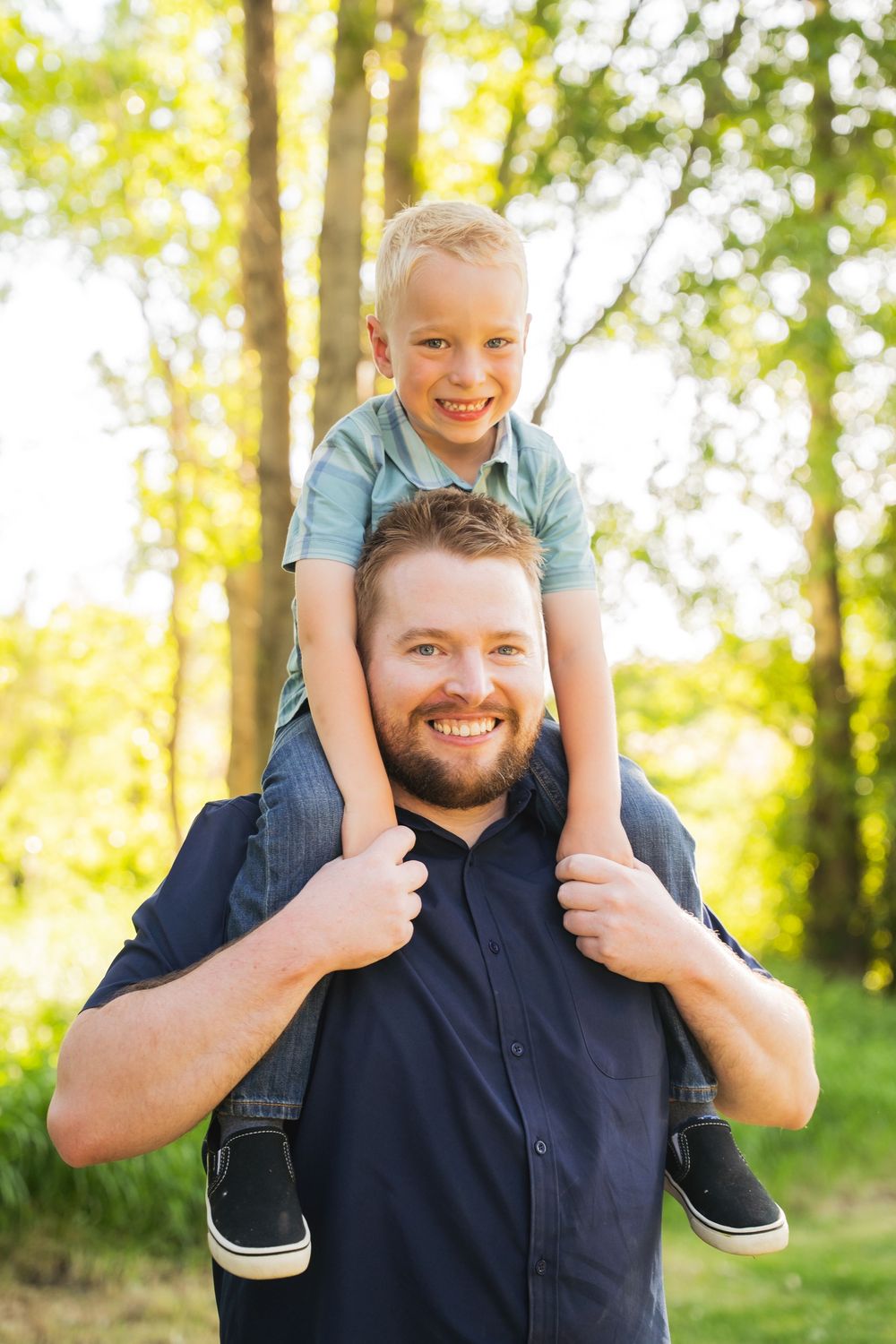 Happy playful moment captured outdoors in a sunlit wooded area with natural foliage in the background.