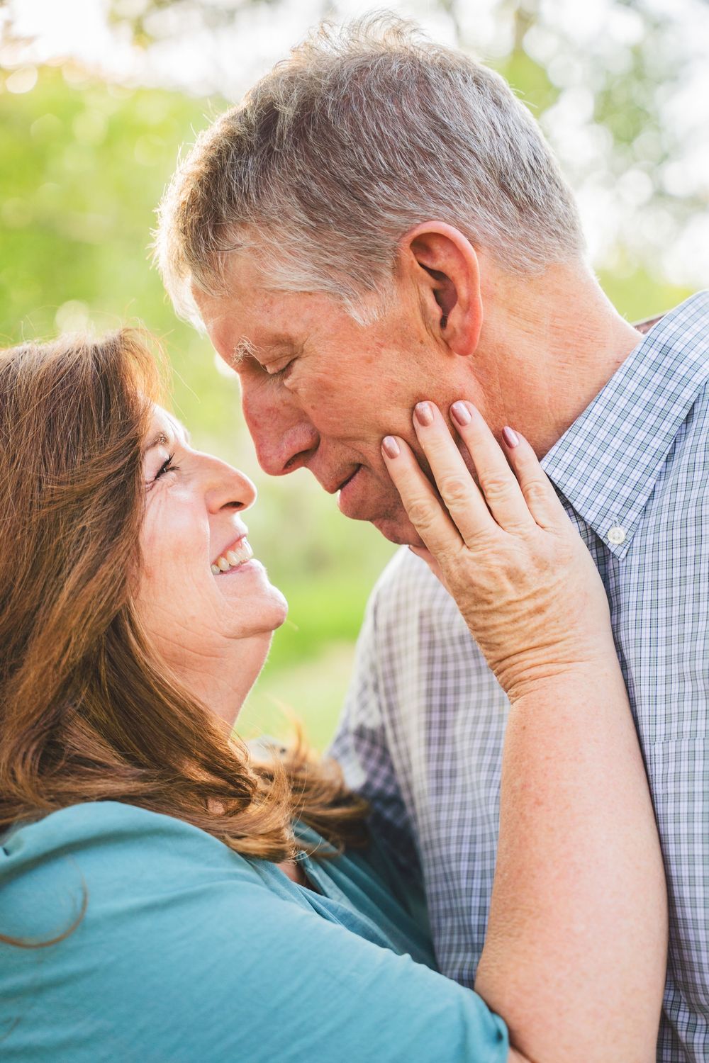 An intimate moment between a loving couple sharing an affectionate embrace outdoors with soft natural lighting.