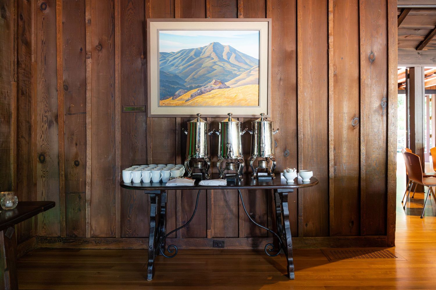 A panoramic view of a rustic wood-paneled interior hallway with mountain landscape artwork and wall sconces.