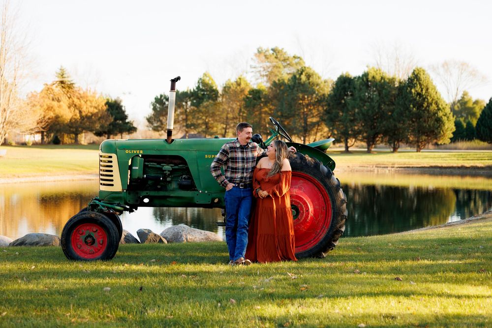A series of vintage tractors displayed in a grassy field during golden hour sunset lighting.