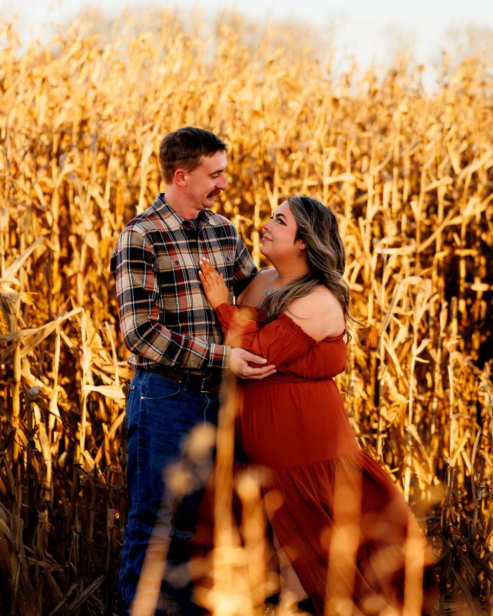 A couple shares tender moments in a golden cornfield during sunset, creating a romantic autumn scene.