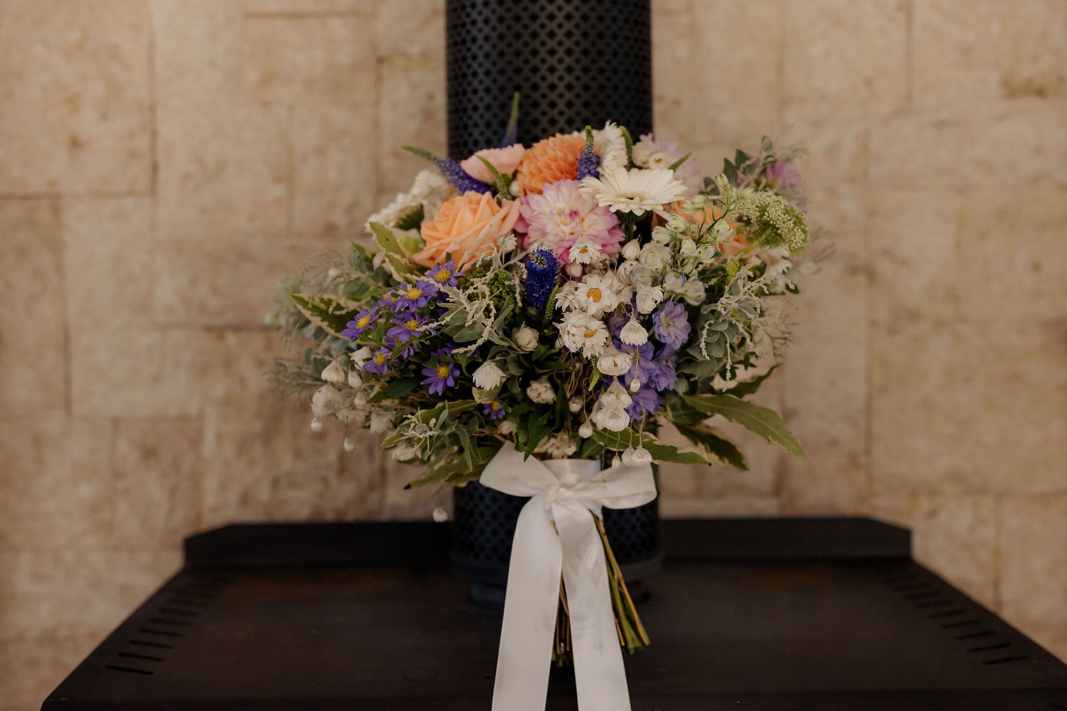 Wedding aisle in an elegant church adorned with floral arrangements on white columns and rustic stone walls.
