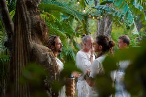 Group gathered for an intimate outdoor ceremony among tropical foliage and trees.