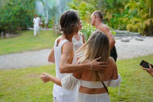 Friends sharing warm embraces during a casual outdoor gathering while wearing all white.