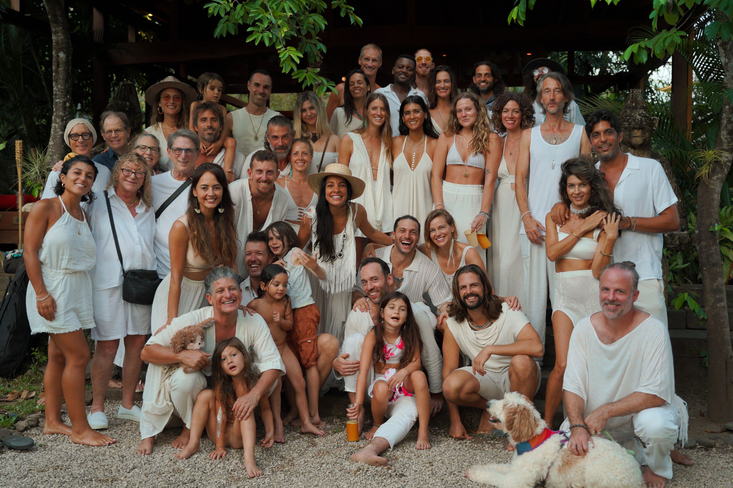 Large group dressed in white gathered outdoors for a group photo.