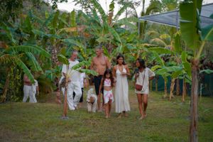 People walking through a lush tropical garden setting in white attire.
