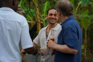 Three people share a lighthearted conversation at an outdoor social gathering.