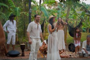 People celebrating in a lush tropical garden setting wearing all white attire.