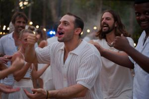 People in white clothing celebrating enthusiastically at an outdoor party.