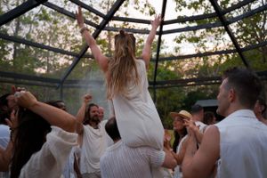 People celebrating at an outdoor party with someone being lifted up in celebration.