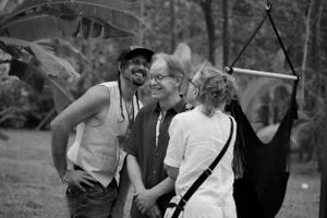 Three people sharing a lighthearted moment together outdoors in black and white photography.